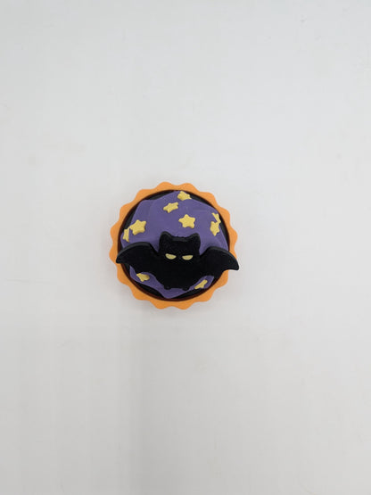Top view of bat cupcake clicker showing black bat and yellow star sprinkles on purple frosting