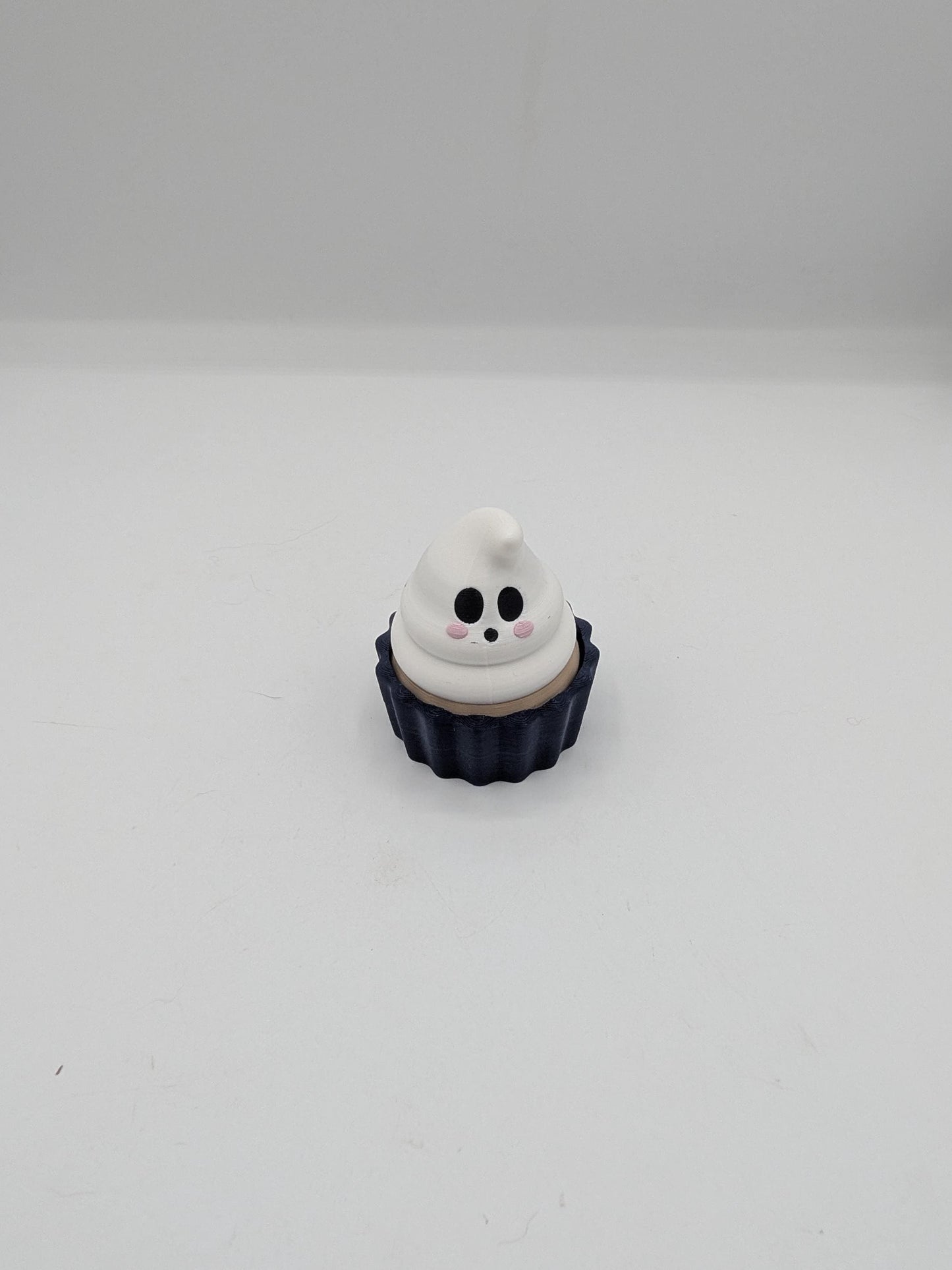 Front view of ghost cupcake clicker fidget with smiling ghost swirl and blushing cheeks
