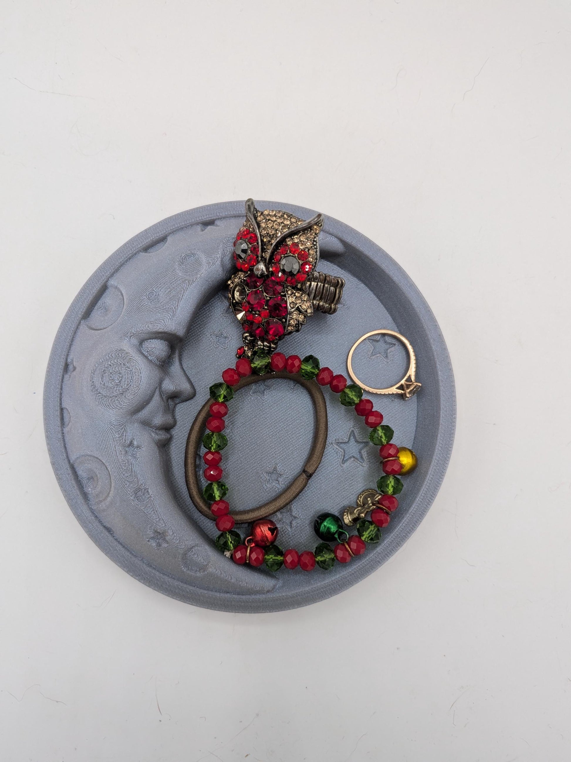 Celestial moon trinket tray holding an owl ring, beaded bracelet, rose gold ring, and hair tie — jewelry storage example