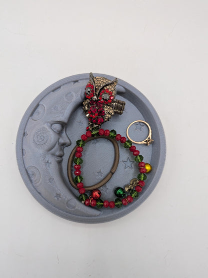 Celestial moon trinket tray holding an owl ring, beaded bracelet, rose gold ring, and hair tie — jewelry storage example