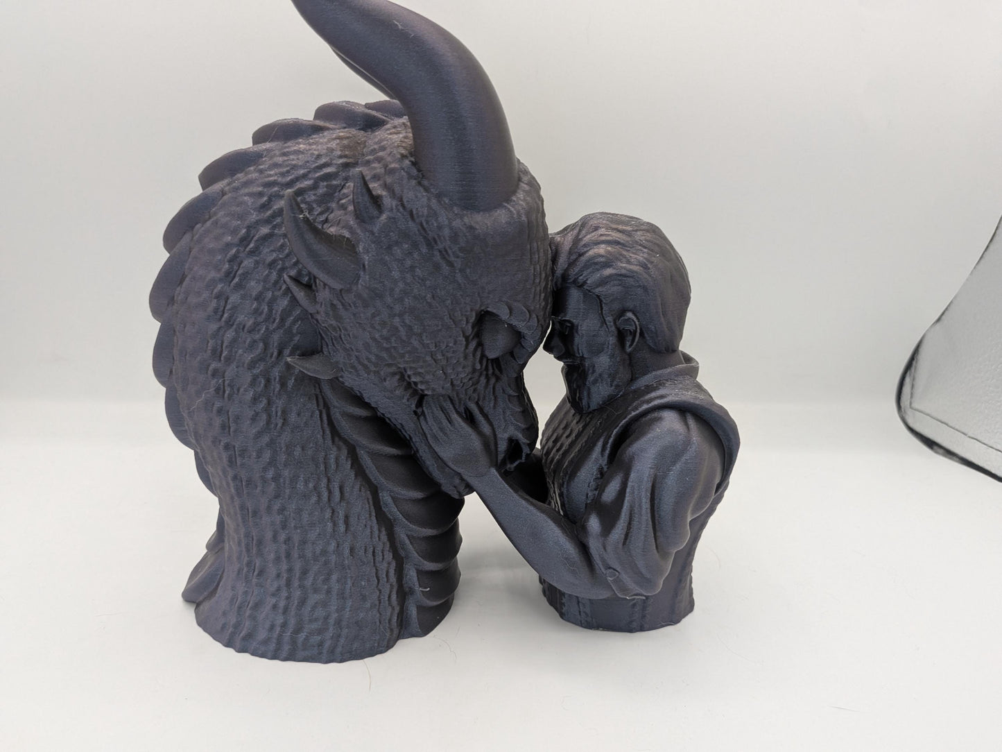 Close view of the male rider dragon bonding statue showing textured dragon scales and sculpted hair detail