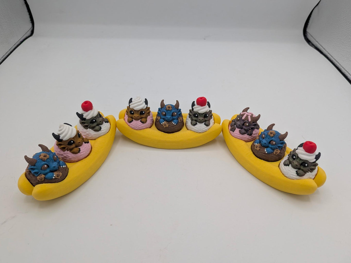 Three dragon banana split clickers showing assorted dragon colors and random toppings