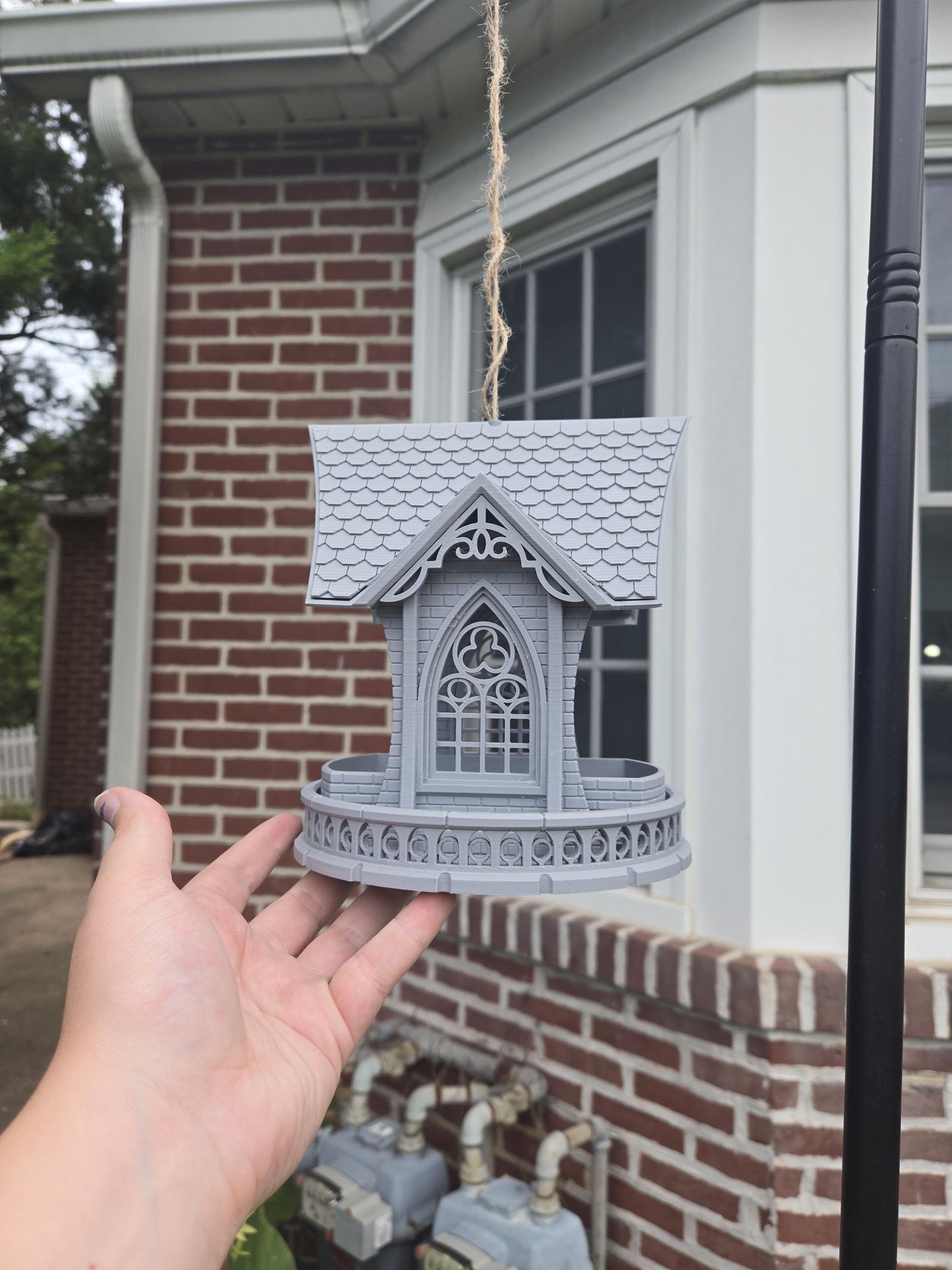 Gothic church bird feeder held in hand outdoors for size reference