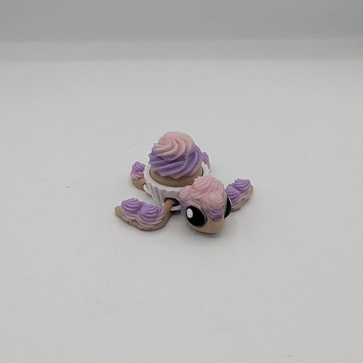 Cupcake turtle key clicker fidget facing forward with big eyes and pink purple frosting, 3D printed