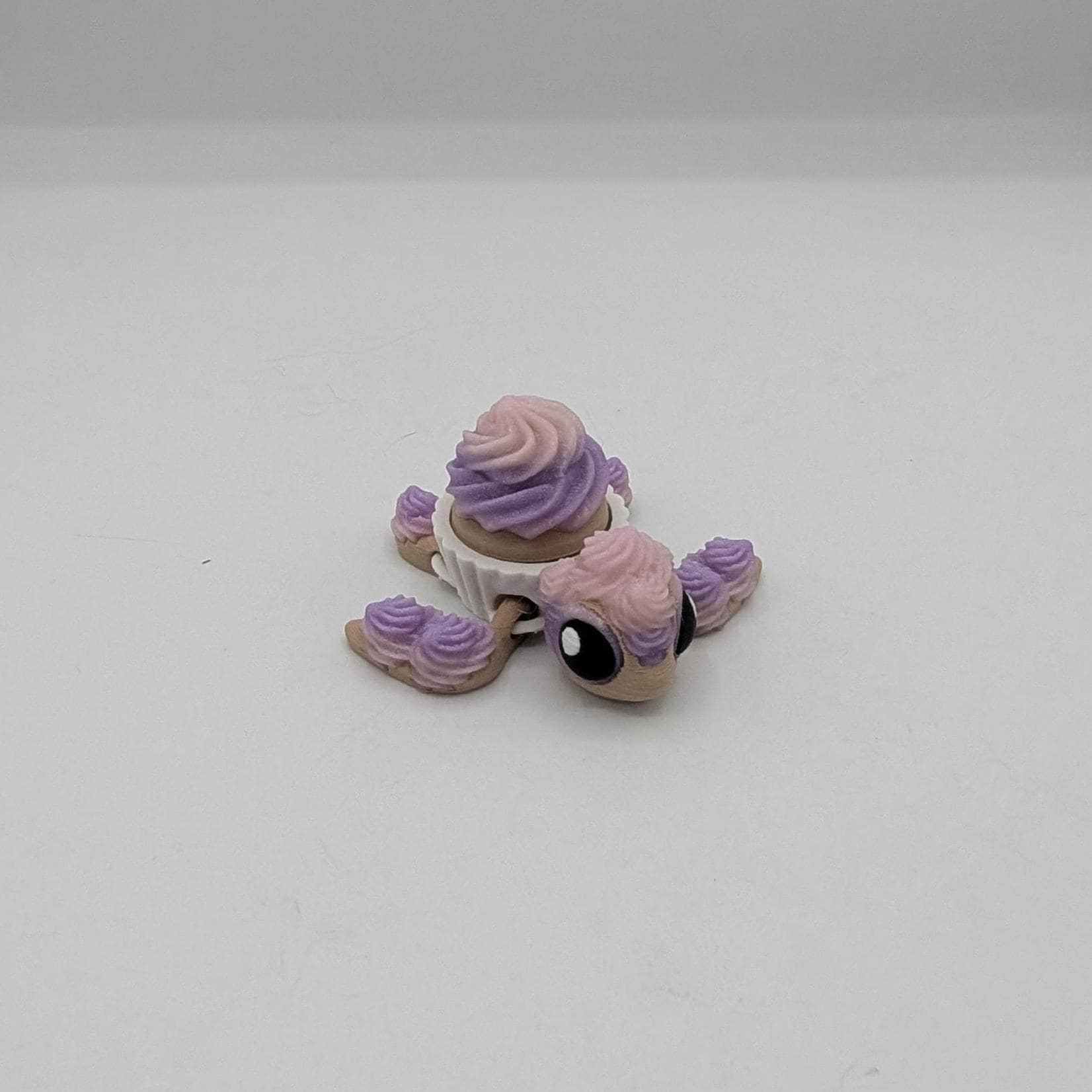 Cupcake turtle key clicker fidget facing forward with big eyes and pink purple frosting, 3D printed