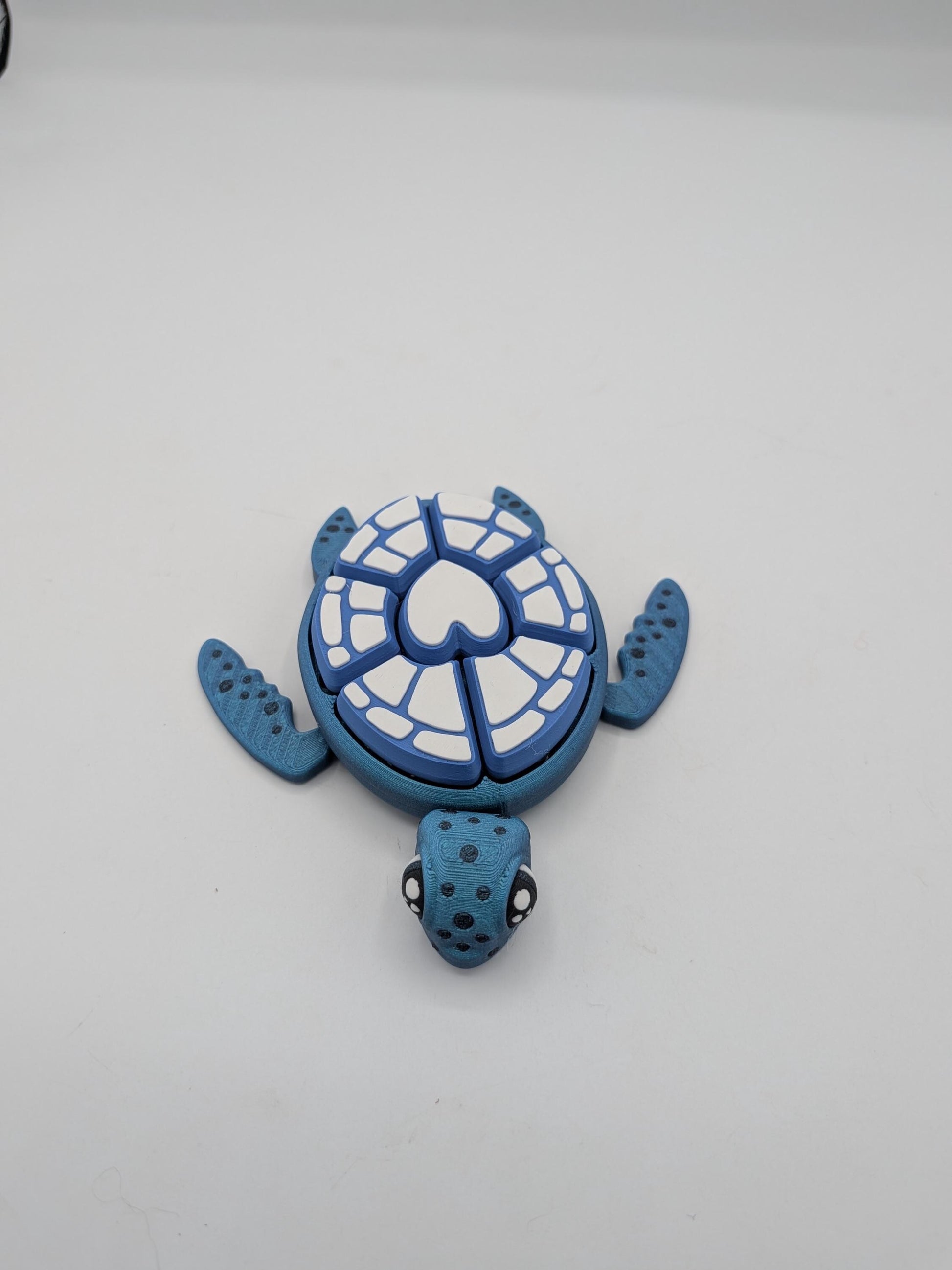 Blue turtle mechanical clicker fidget with white heart design shell and spotted head, viewed from above