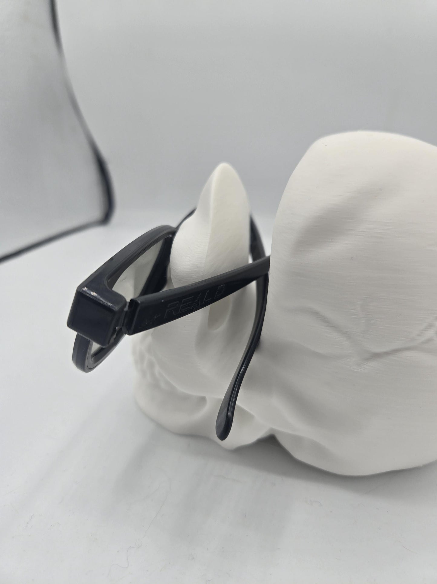 Rear view of eyeglasses resting on the skull holder with temple arms supported over the cranium