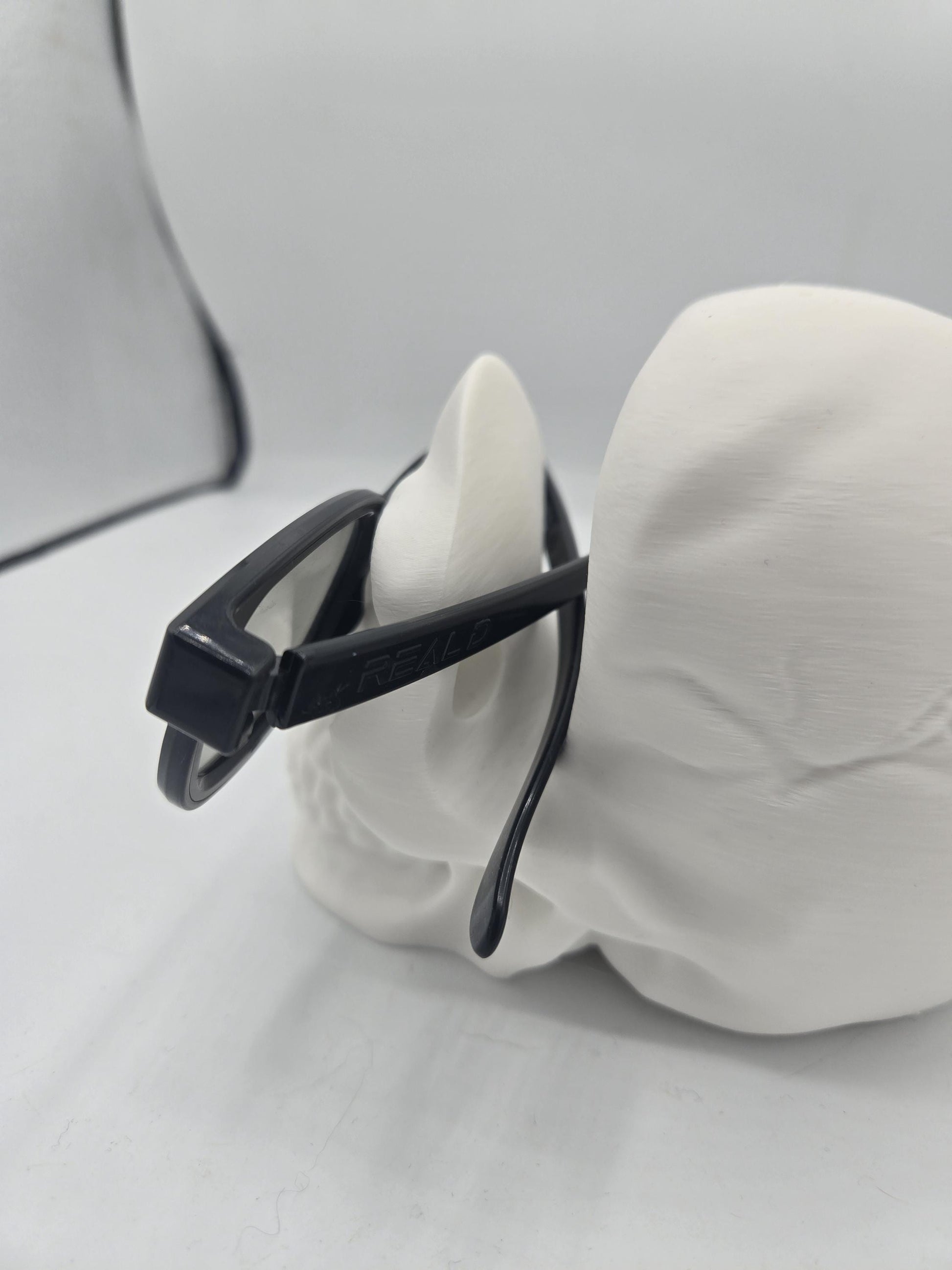 Rear view of eyeglasses resting on the skull holder with temple arms supported over the cranium