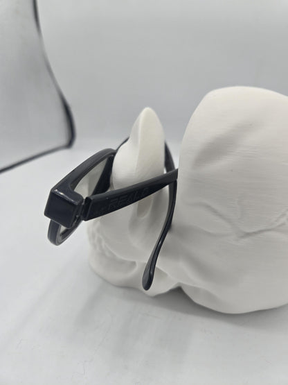 Rear view of eyeglasses resting on the skull holder with temple arms supported over the cranium