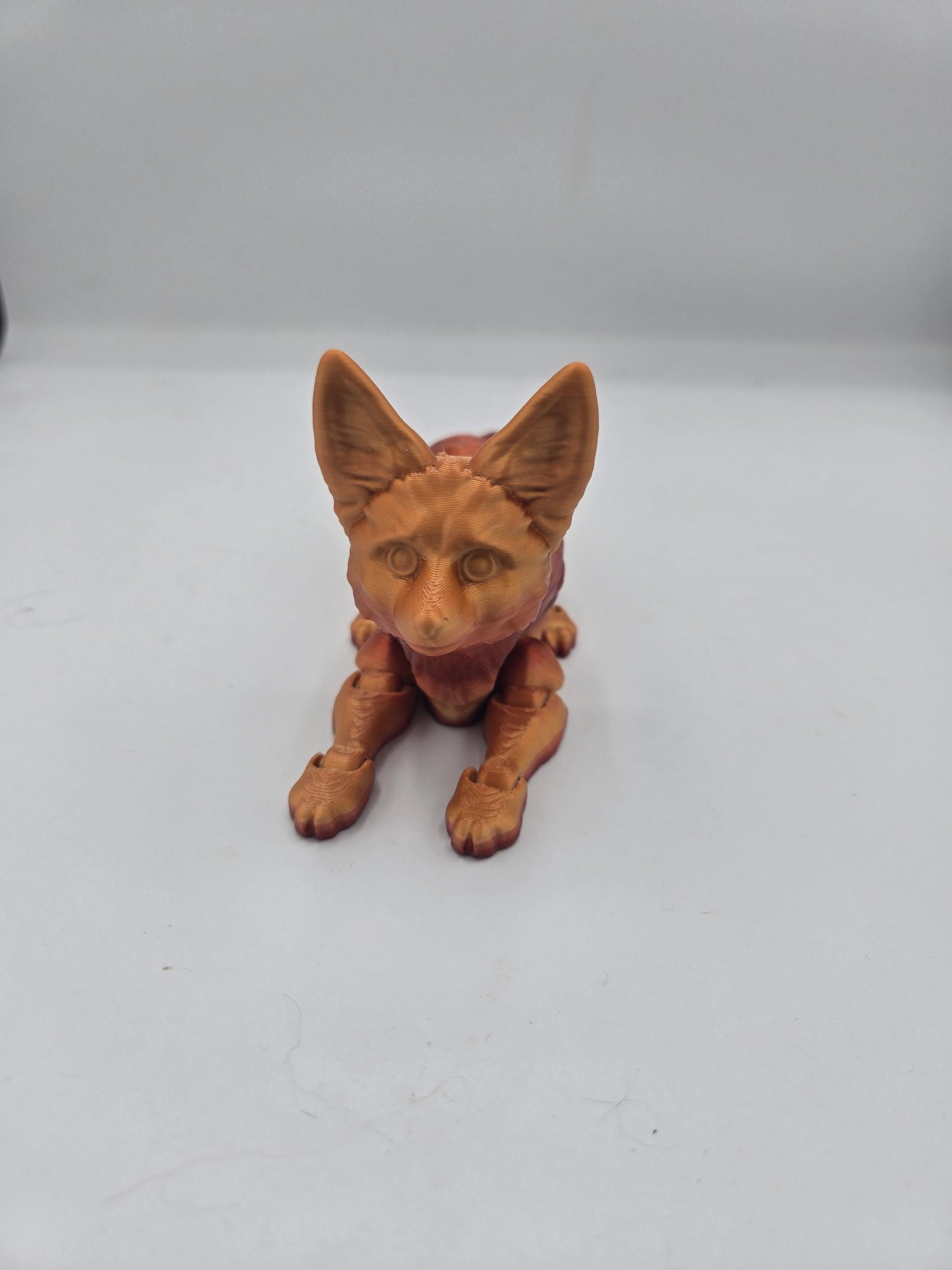 Front view of articulated fennec fox figurine with oversized ears and front paws stretched forward