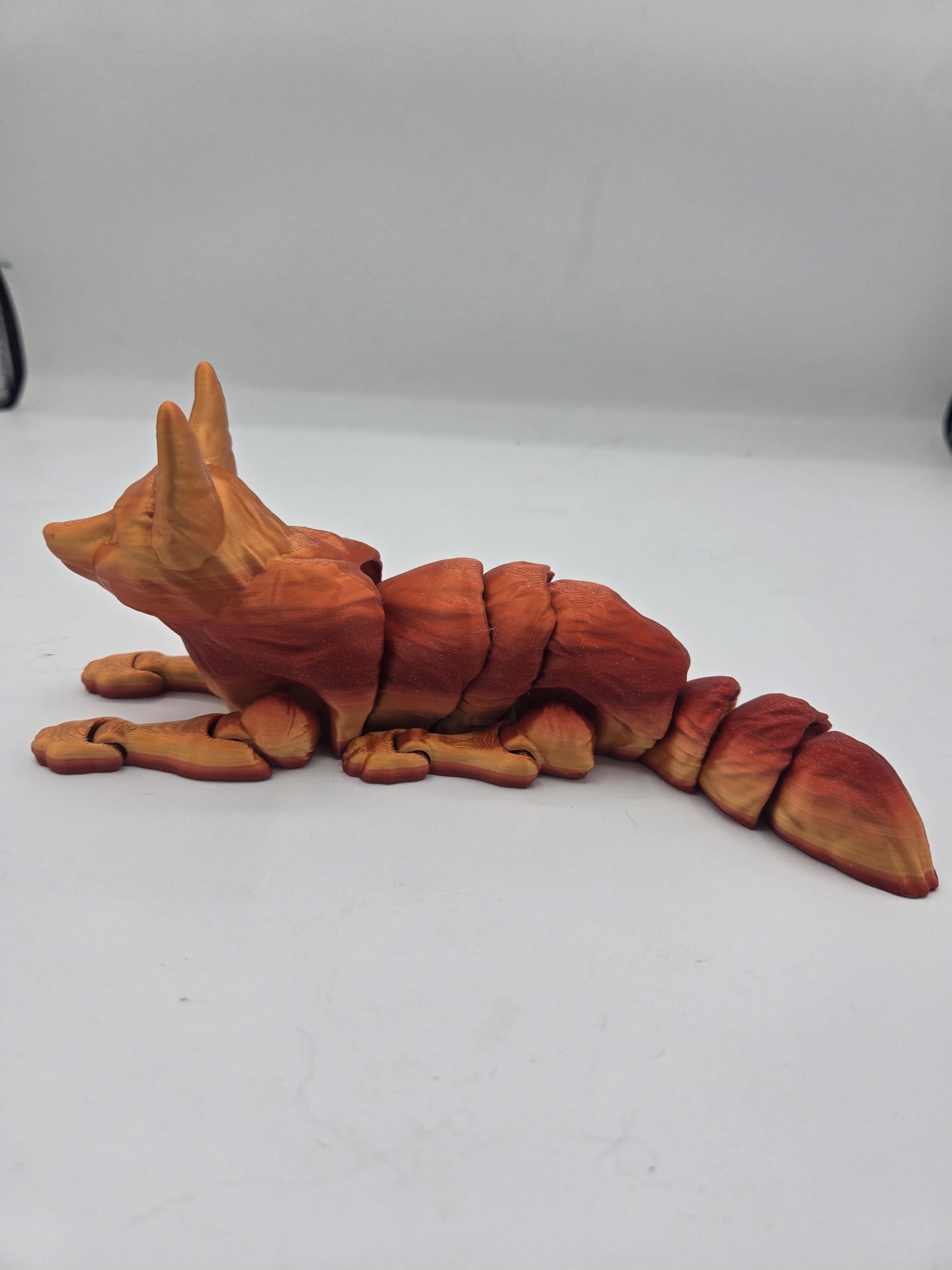 Fennec fox flexi figurine lying down, side view of segmented articulated body and thick tail