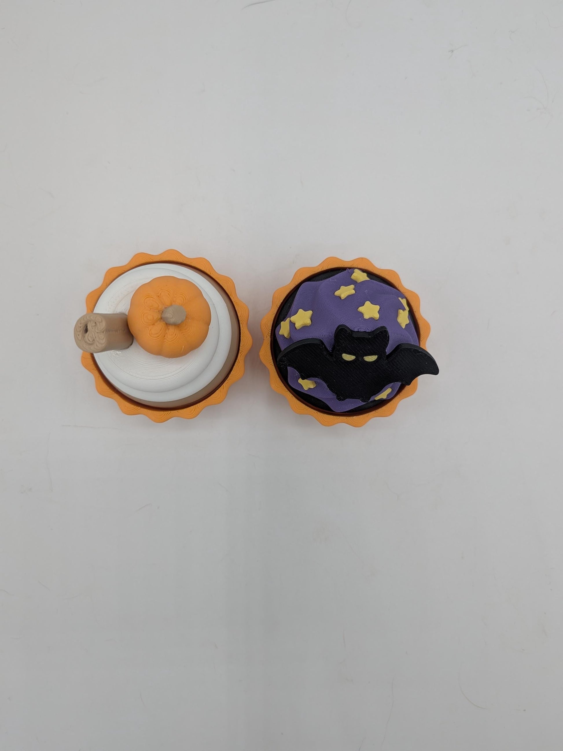 Top view of pumpkin spice and bat Halloween cupcake clicker fidgets side by side