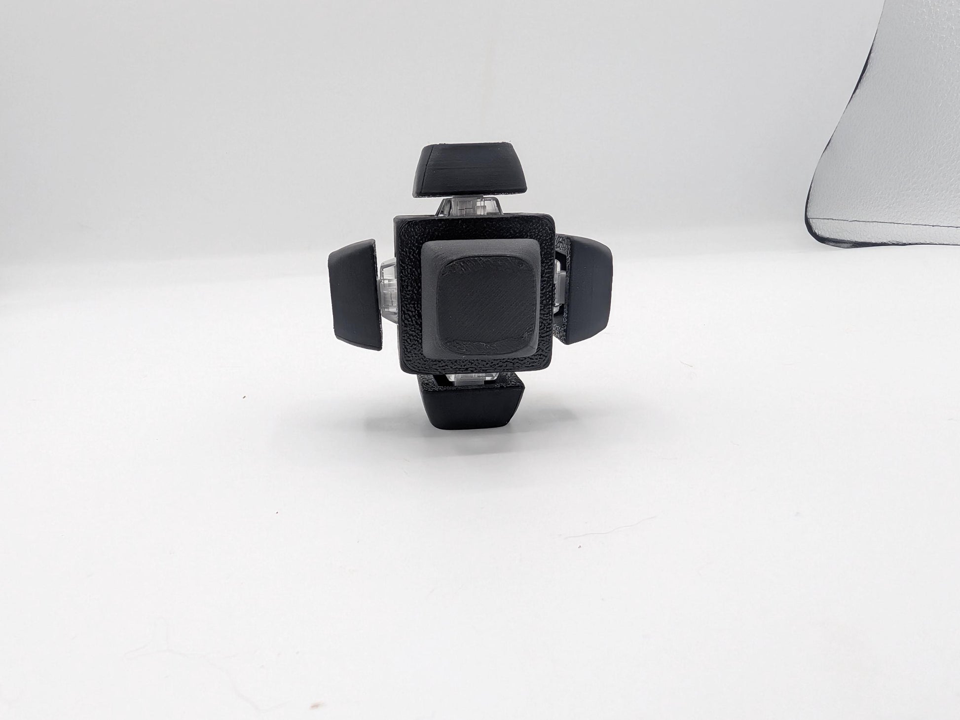 Black clicker cube fidget with a mechanical key switch keycap on every side, front view, 3D printed