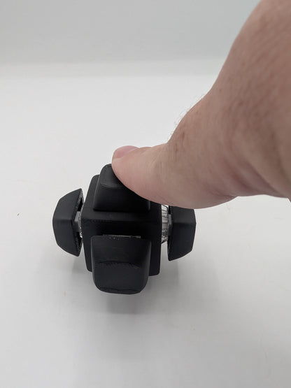 Hand clicking a side keycap on the black clicker cube desk fidget, 3D printed