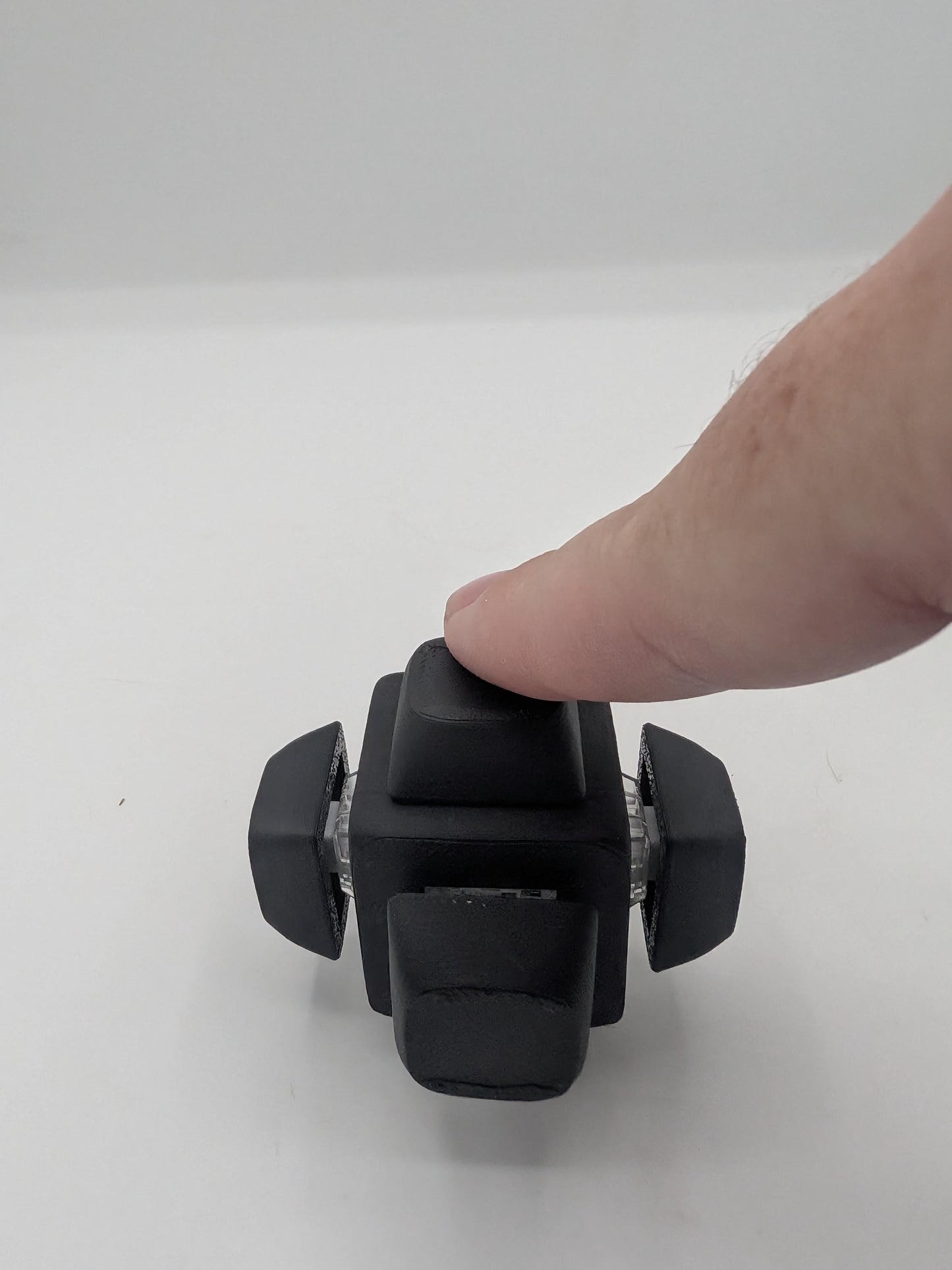 Finger pressing the top keycap of the black clicker cube key switch fidget, 3D printed