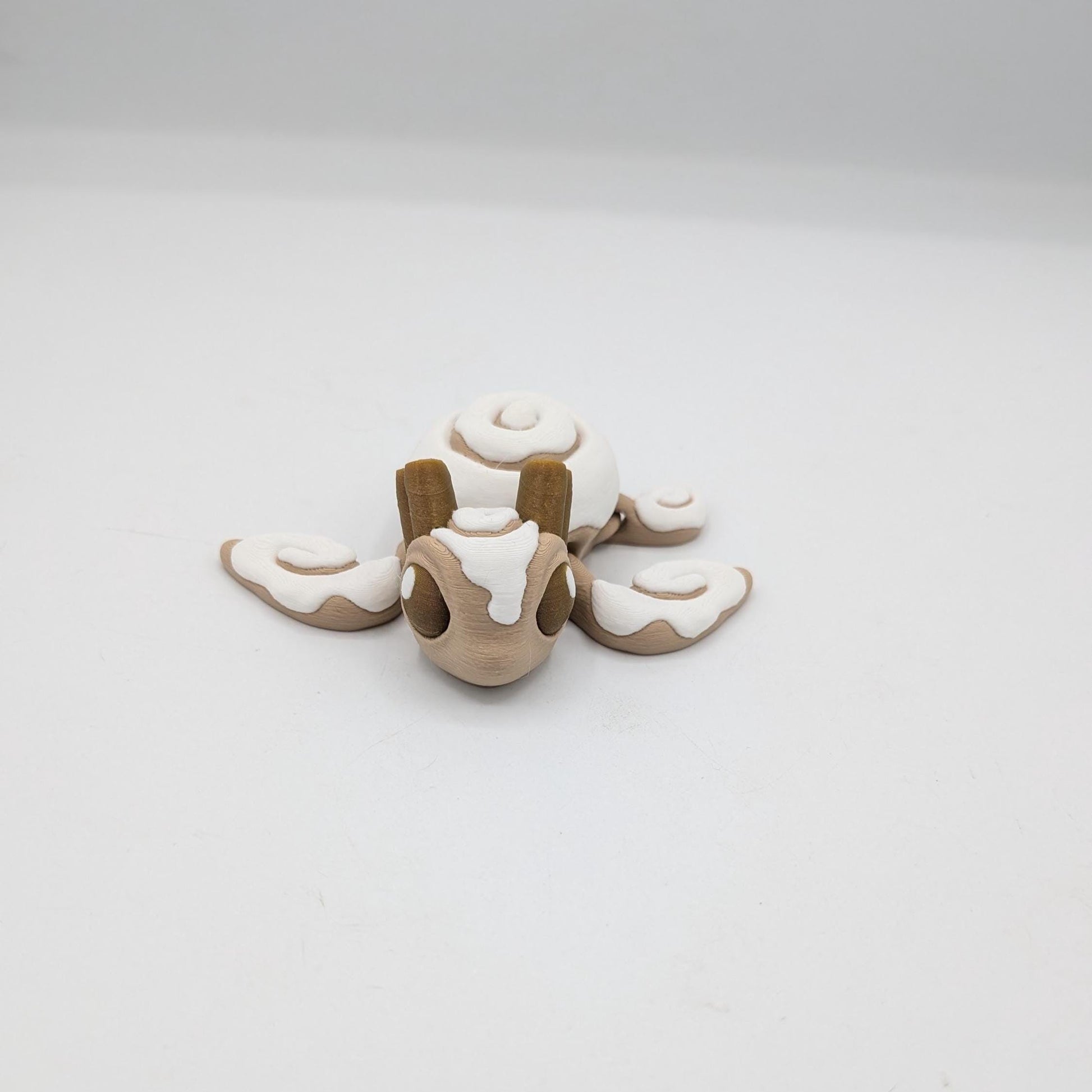 Cinnamon Bun Turtle flexi 3D print front view — frosted face with cinnamon sticks atop the head