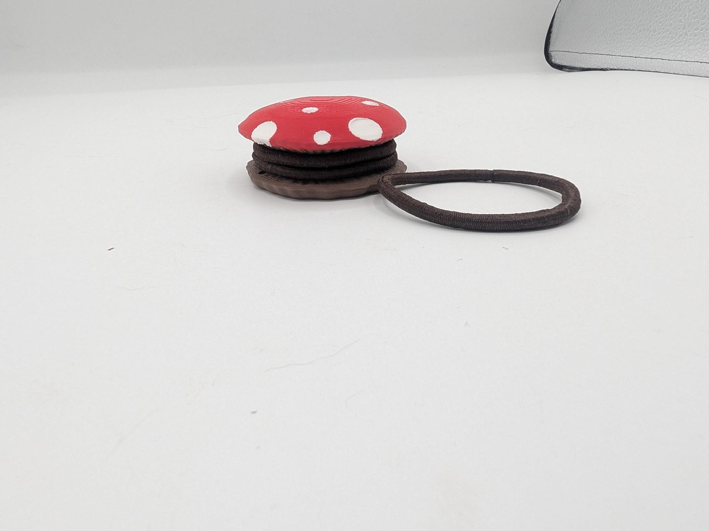 Side view of the mushroom hair tie holder with brown hair ties stacked between the spotted red cap and the brown base