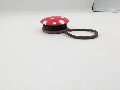 Side view of the mushroom hair tie holder with brown hair ties stacked between the spotted red cap and the brown base