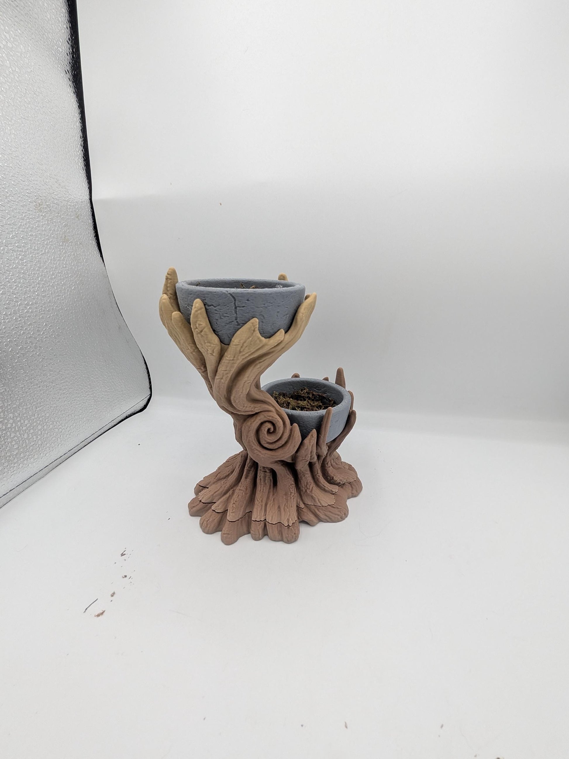 Side view of the spiral tree dual planter showing the swirled trunk detail and rooted base, upper bowl empty and lower bowl holding faux moss