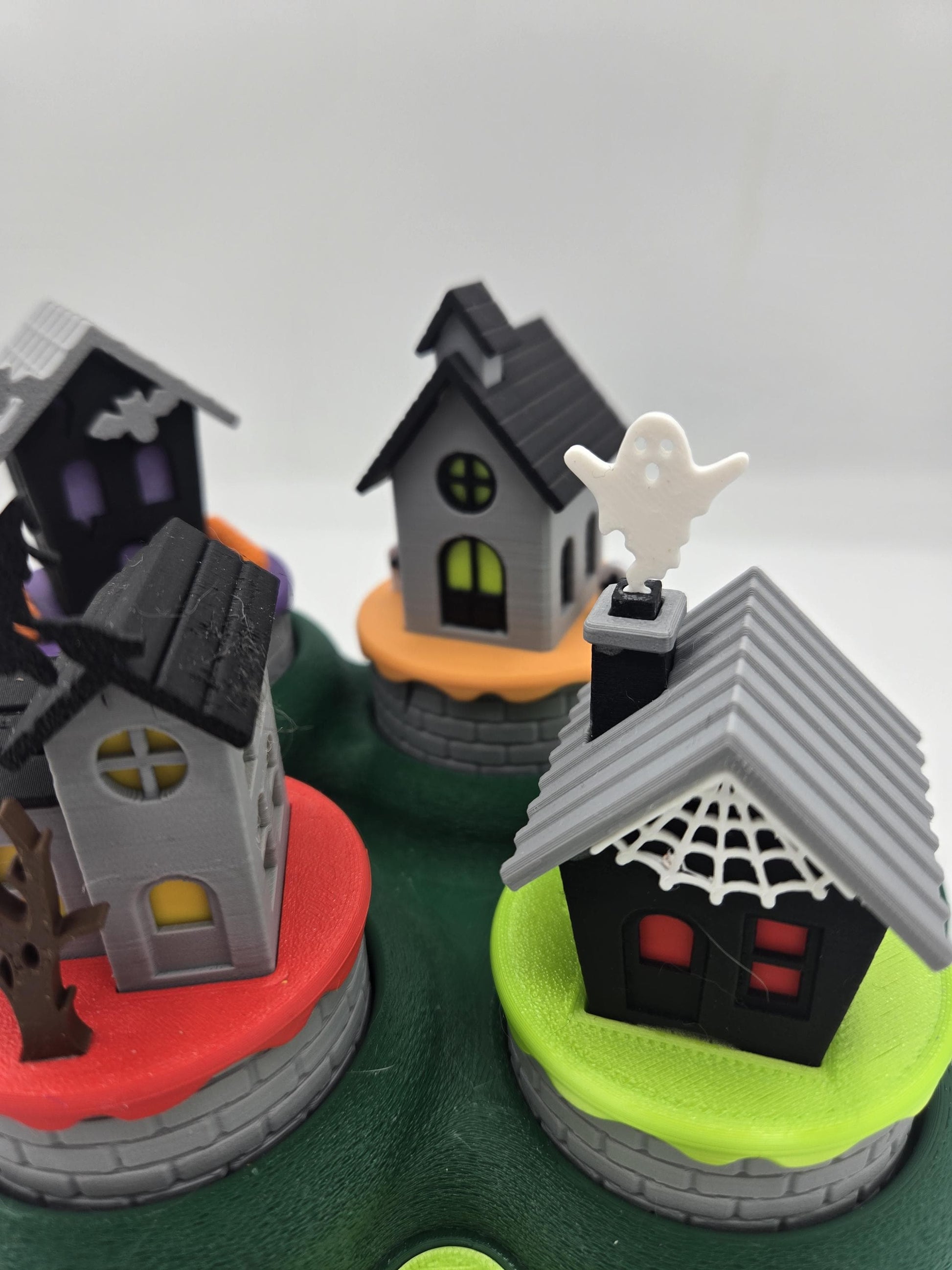 Close-up of the church and the black spiderweb cottage with a ghost rising from its chimney — Halloween mini village tealight houses