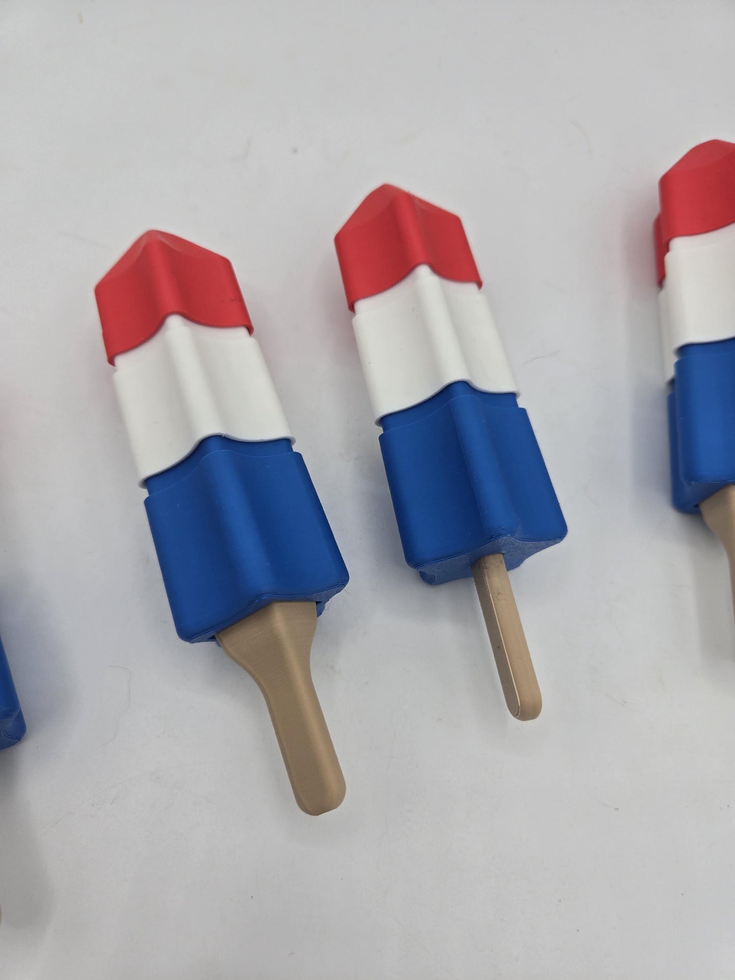 Close view of summer popsicle clickers standing in a row, showing the red, white, and blue sections and tan sticks