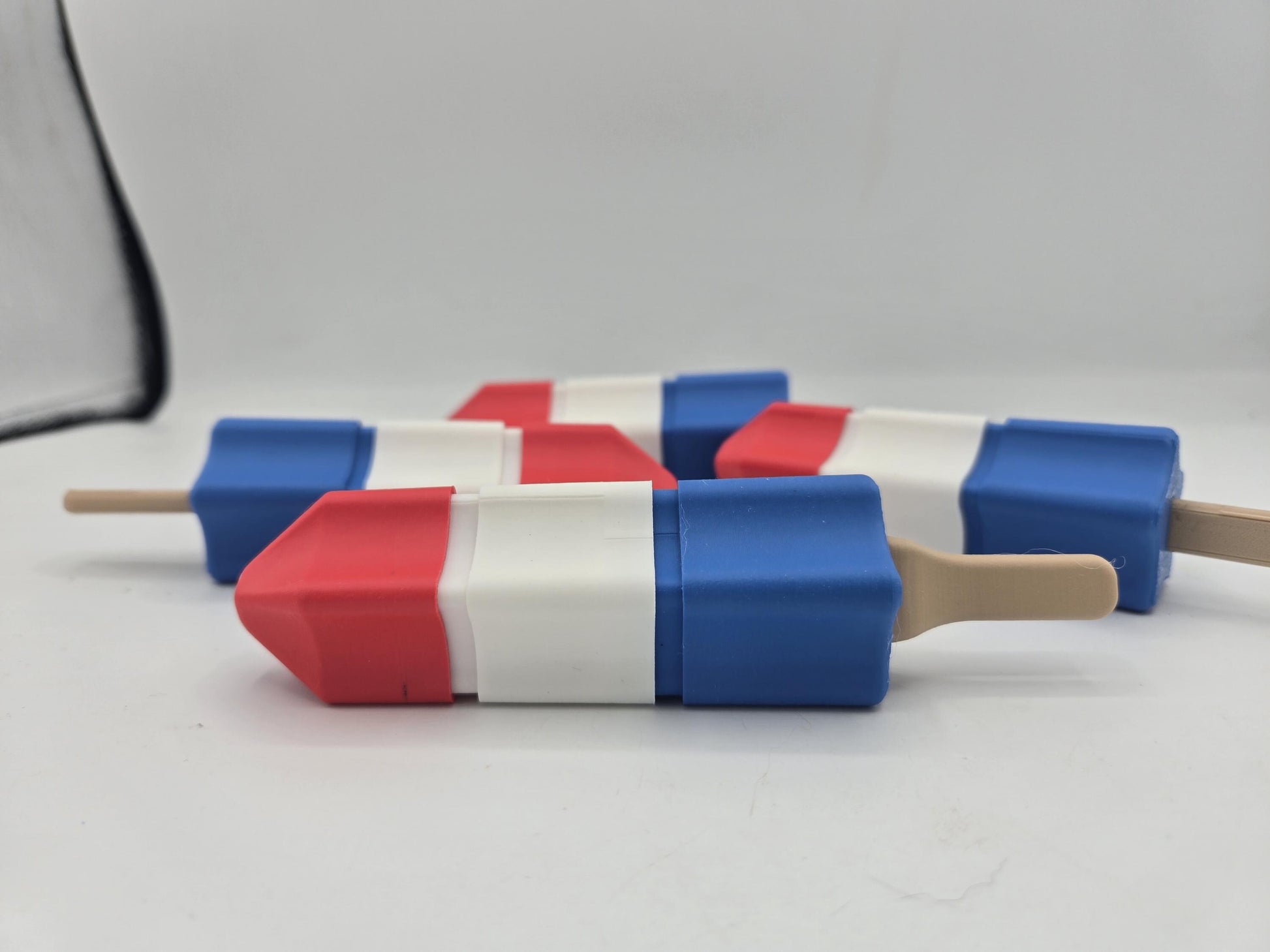 Red, white, and blue rocket popsicle fidget clickers lying on a white surface — 3D printed mechanical key switch toys