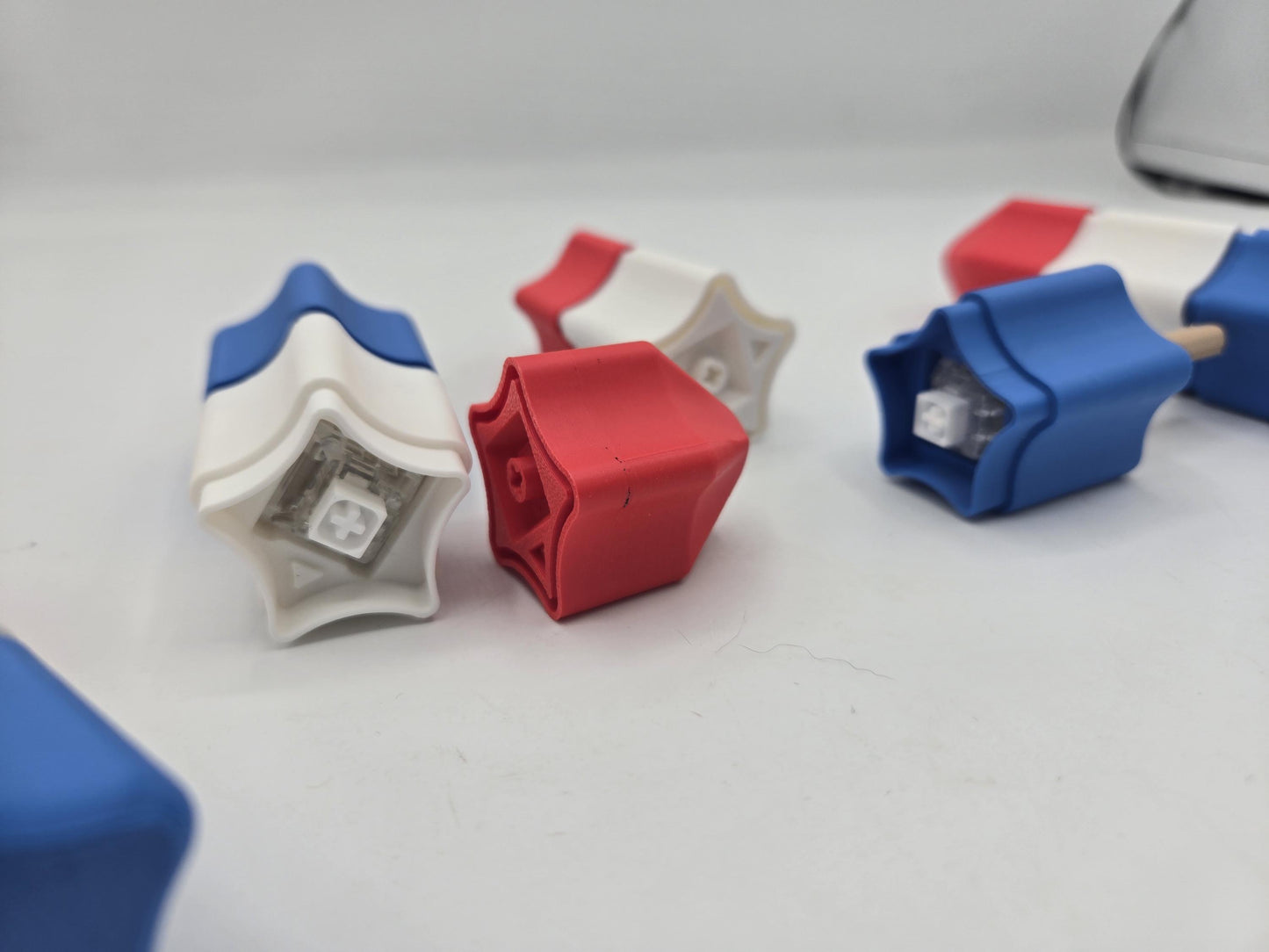 Popsicle clicker sections separated to show the mechanical key switches inside the red, white, and blue 3D printed segments