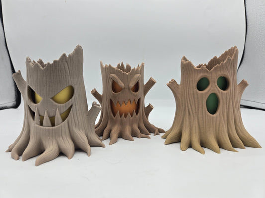 Three 3D printed haunted tree stump tealight holders with different spooky carved faces, shown unlit