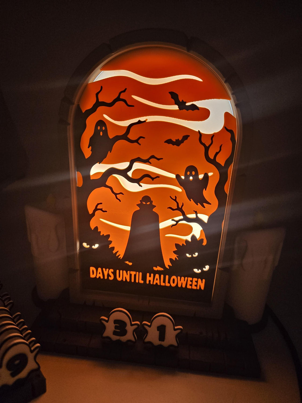 Vampire Halloween Countdown glowing in low light — warm orange LED backlight brings out the vampire, ghost, and bat silhouettes