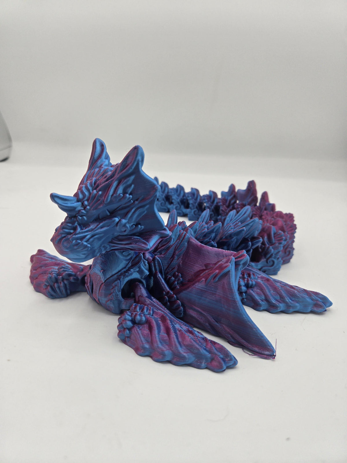Ocean Sea Dragon flexi 3D print in Blue-Purple Dual — front three-quarter view sitting tall with wing fins spread and long articulated tail curling behind