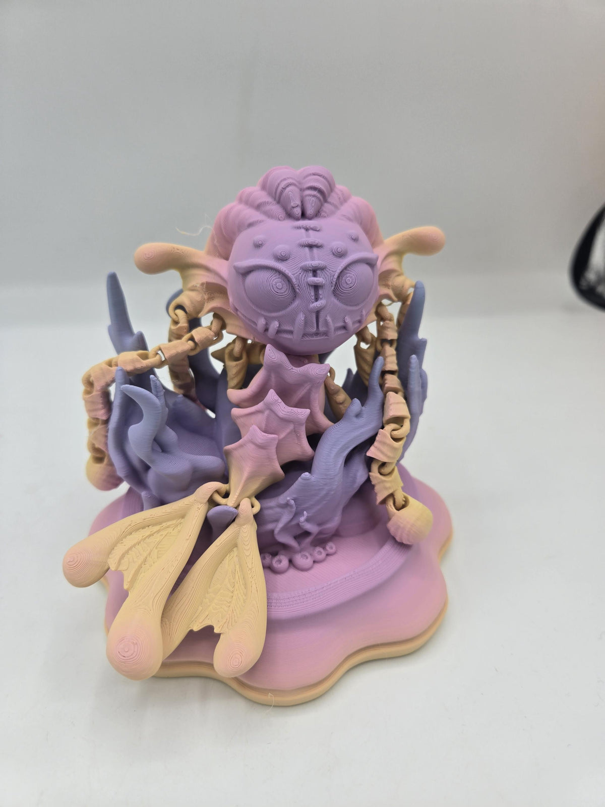 Spooky Mermaid Doll 3D print in pastel pink, purple and cream, posed upright on a wavy display base with articulated arms and tail fins