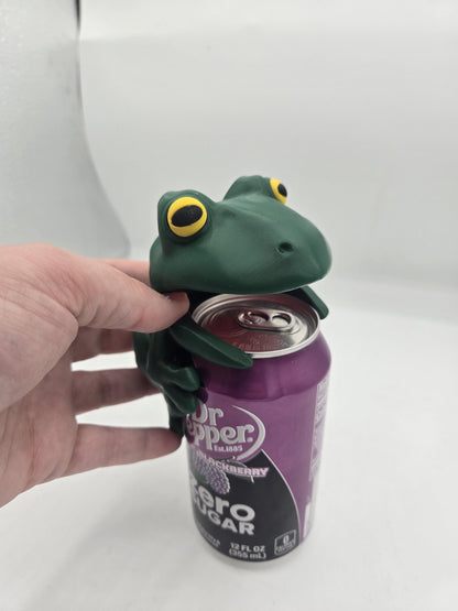 Frog Can Cover 3D print held in hand — fingers lifting the frog's upper jaw off a 12oz can to show how the mouth opens for drinking