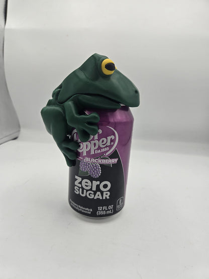 Frog Can Cover 3D print — dark green frog with yellow eyes perched on top of a 12oz soda can, mouth closed over the opening and front legs hugging the can