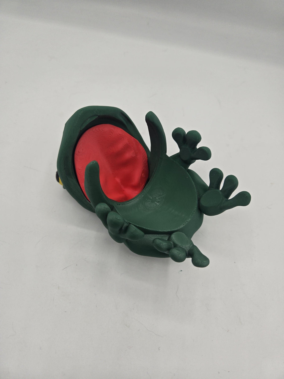 Frog Can Cover 3D print underside view — open mouth showing the red interior and the curved jaw that clips over the can rim, with splayed webbed feet