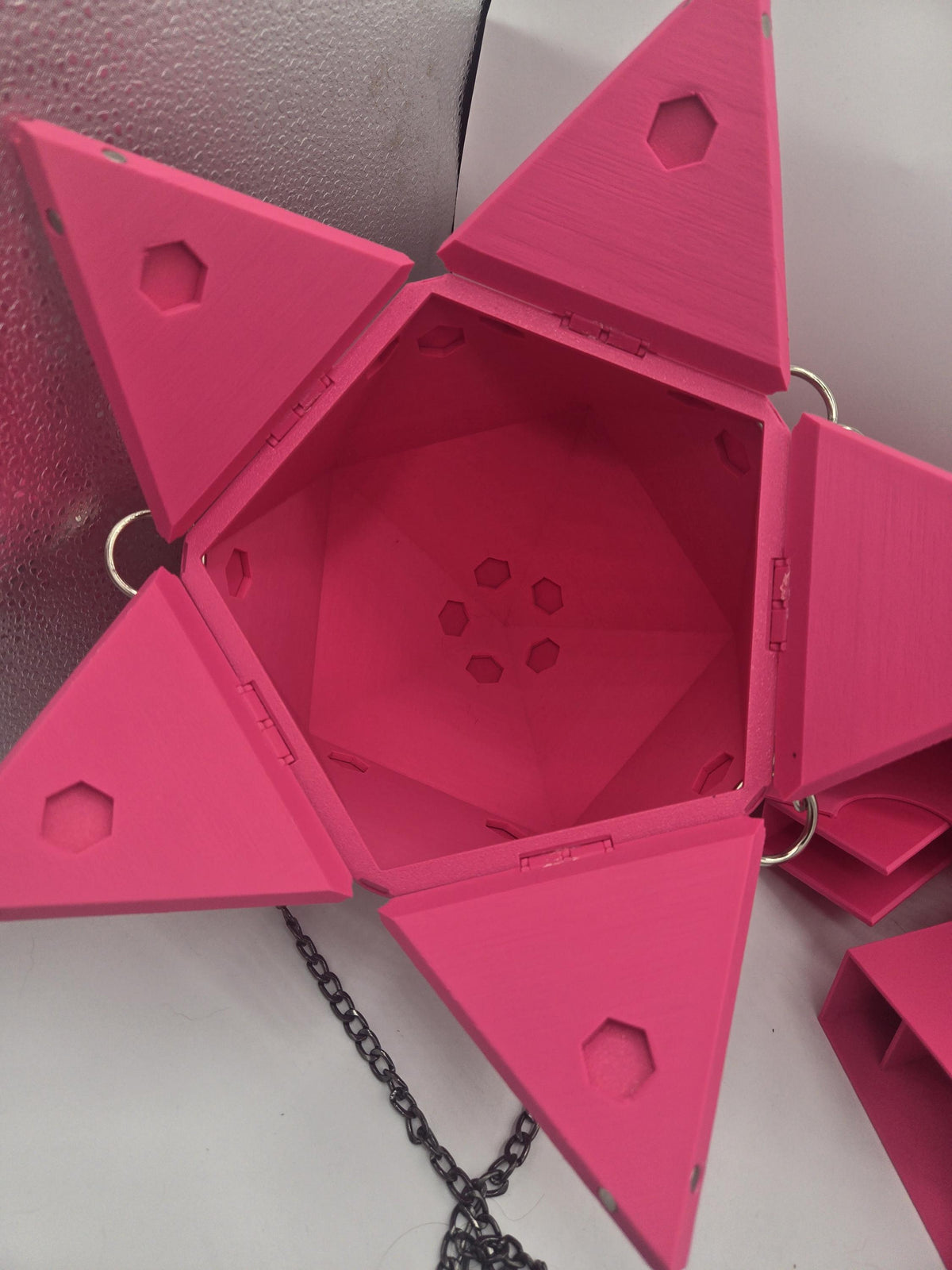 D20 Dice Shaped Purse 3D print in pink opened flat from above, empty hexagonal interior with hinged triangular panels and silver chain rings