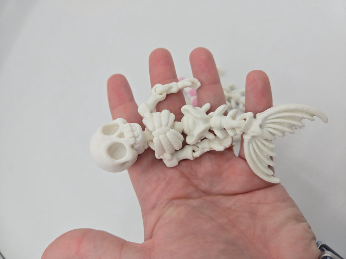 Flexi Mermaid Skeleton 3D print plain white style lying across a hand, showing the skull, ribcage, jointed arms and fanned tail fin