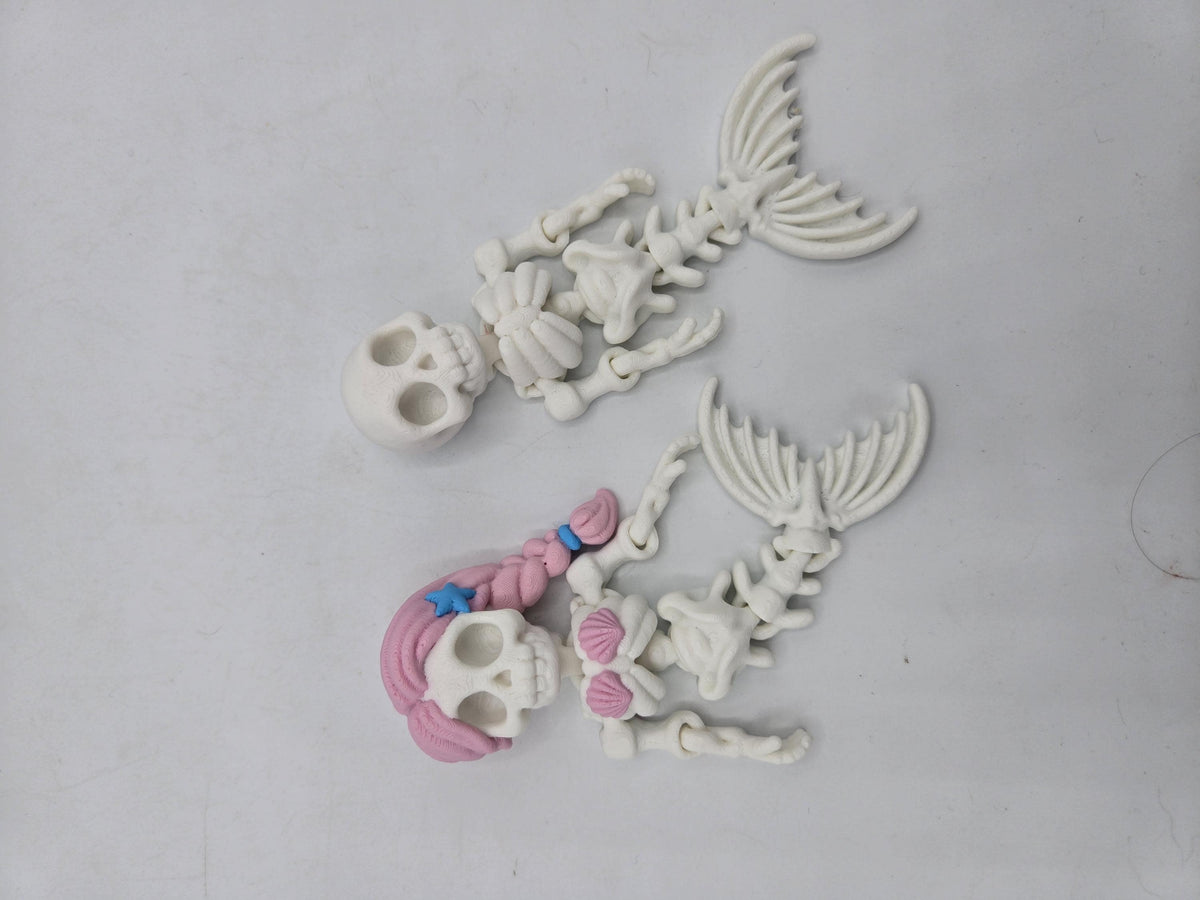 Flexi Mermaid Skeleton 3D print top view of the plain and Hair + Clam Shells styles laid out flat, poseable arms and segmented skeletal tails